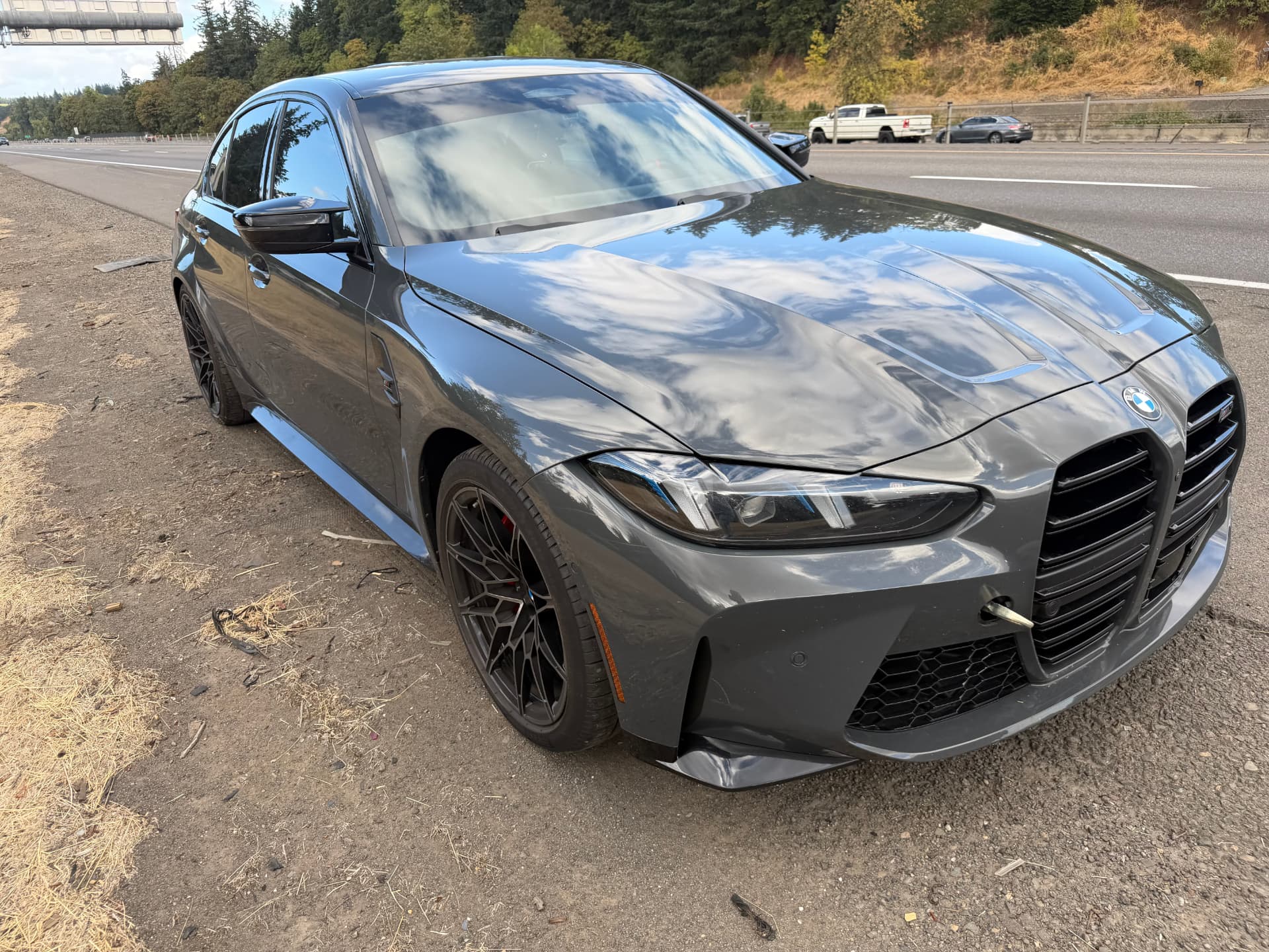 Grey BMW M3 with front bumper damage on the roadside before collision repair