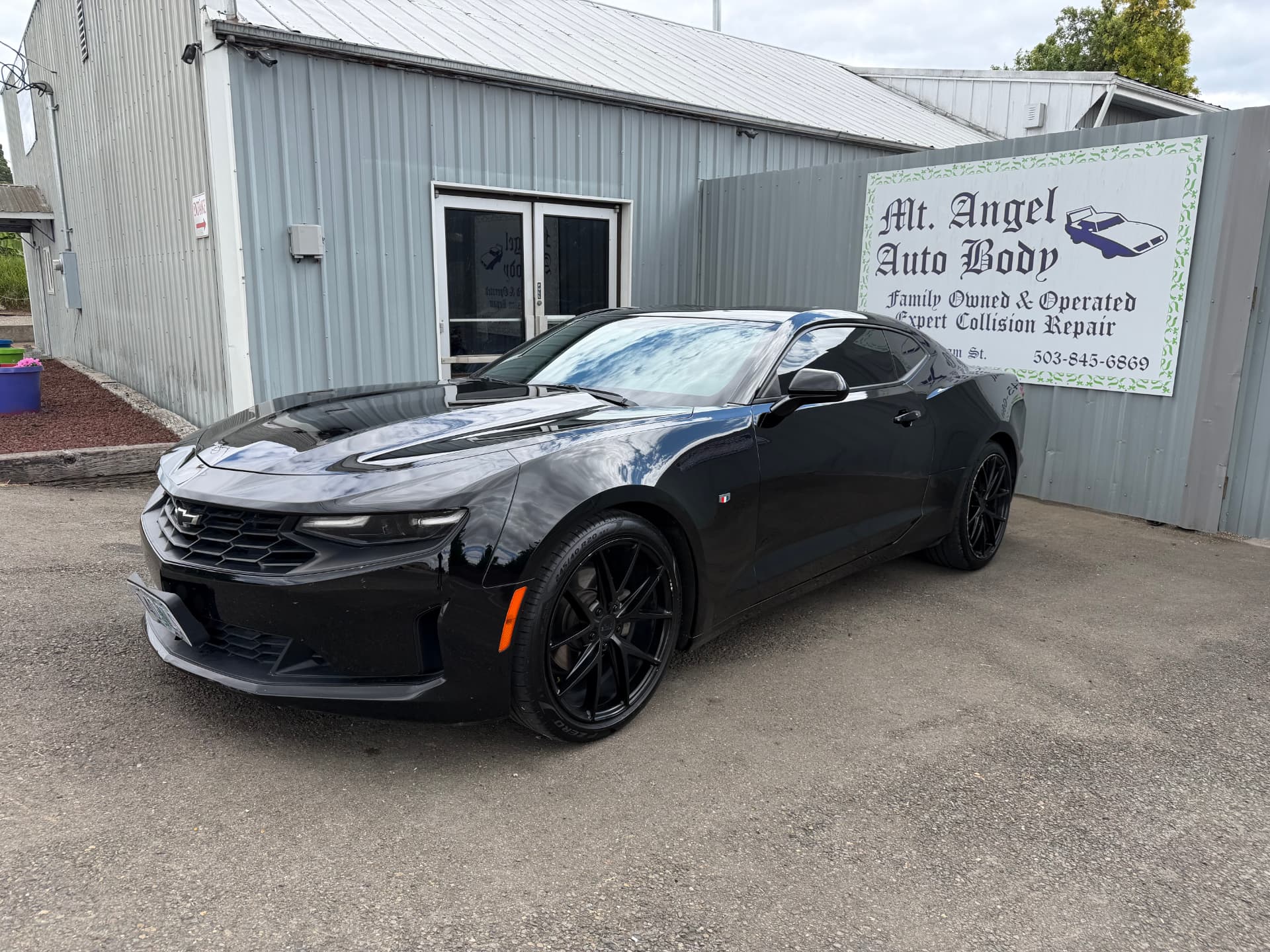 Finished gloss black Chevrolet Camaro parked outside the Mt. Angel Auto Body shop
