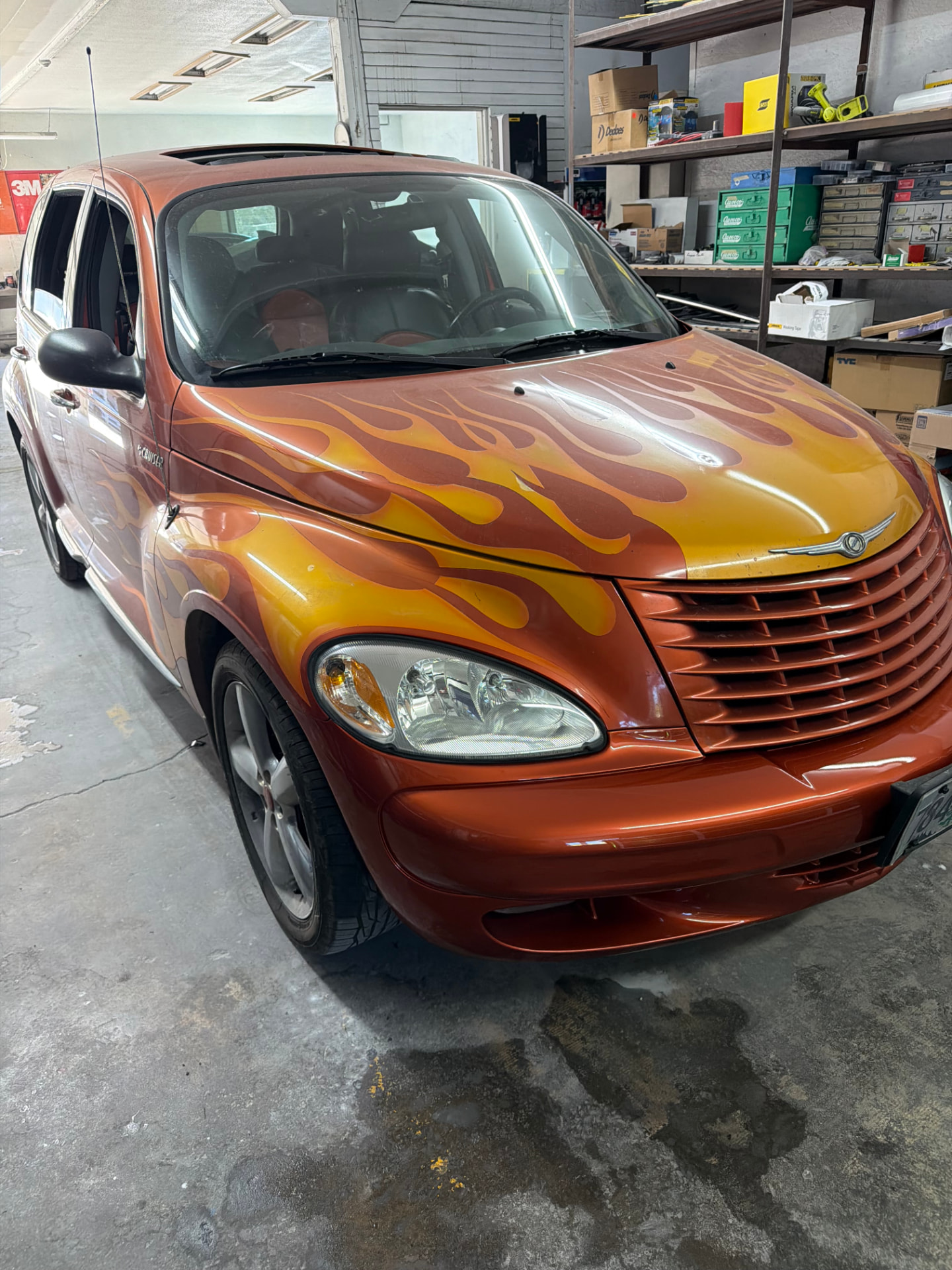 Orange Chrysler PT Cruiser with custom airbrushed flame paint job inside the shop